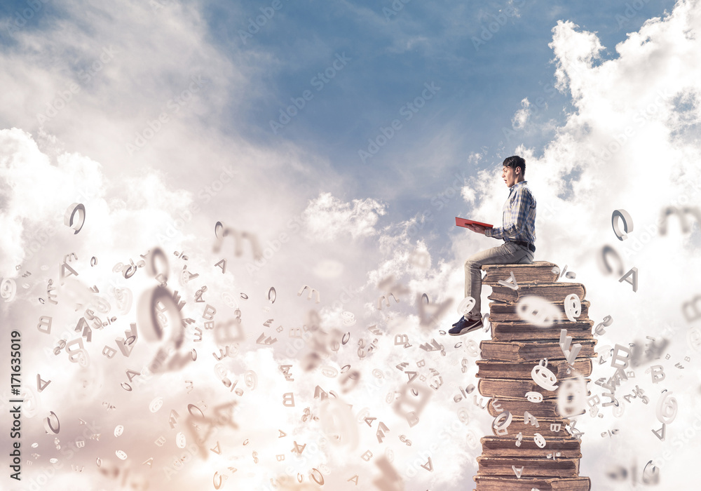 Man student on stack reading book and symbols flying around Man student on stack reading book and symbols flying around