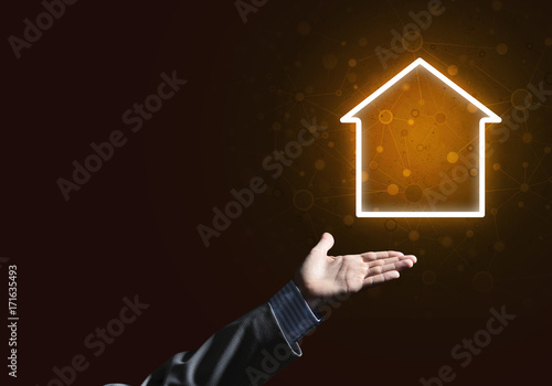 Conceptual image with hand pointing at house or main page icon on dark background