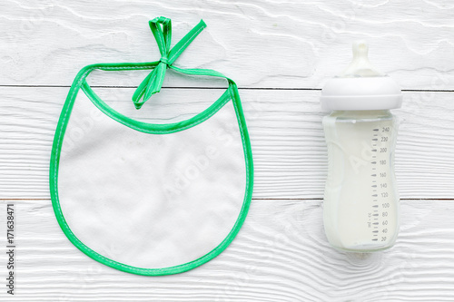 preparation of mixture baby feeding with infant formula powdered milk in bottle with bib on white background top view mock up