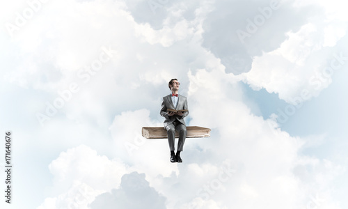 Young businessman or student floating in blue sky and studying the science
