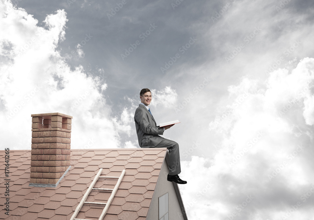 Student guy in suit on brick house roof reading book Student guy in suit on brick house roof reading book