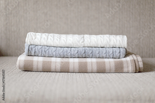 Woolen plaids or sweaters on a grey sofa, winter or autumn season. © shutnica