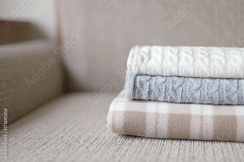 Fototapeta Naklejka Na Ścianę i Meble -  Woolen plaids or sweaters on a grey sofa, winter or autumn season.