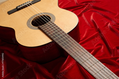acoustic guitar on red velvet fabric, close view of object