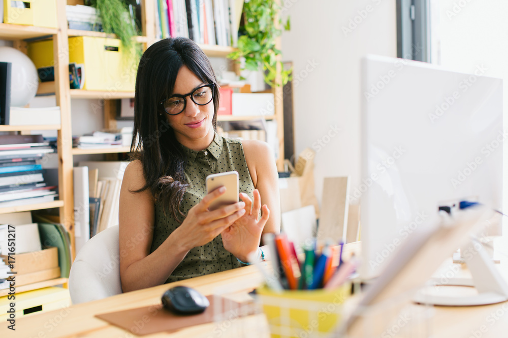 Young female designer using her phone at studio. Young female designer using her phone at studio.