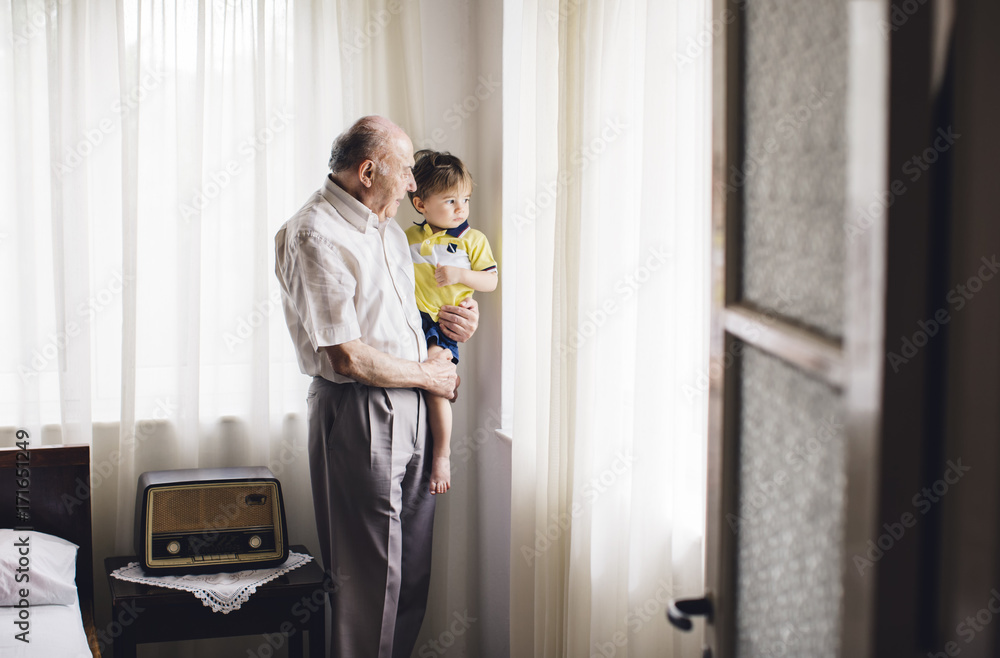 Grandfather with his grandson looking outside of a window Grandfather with his grandson looking outside of a window