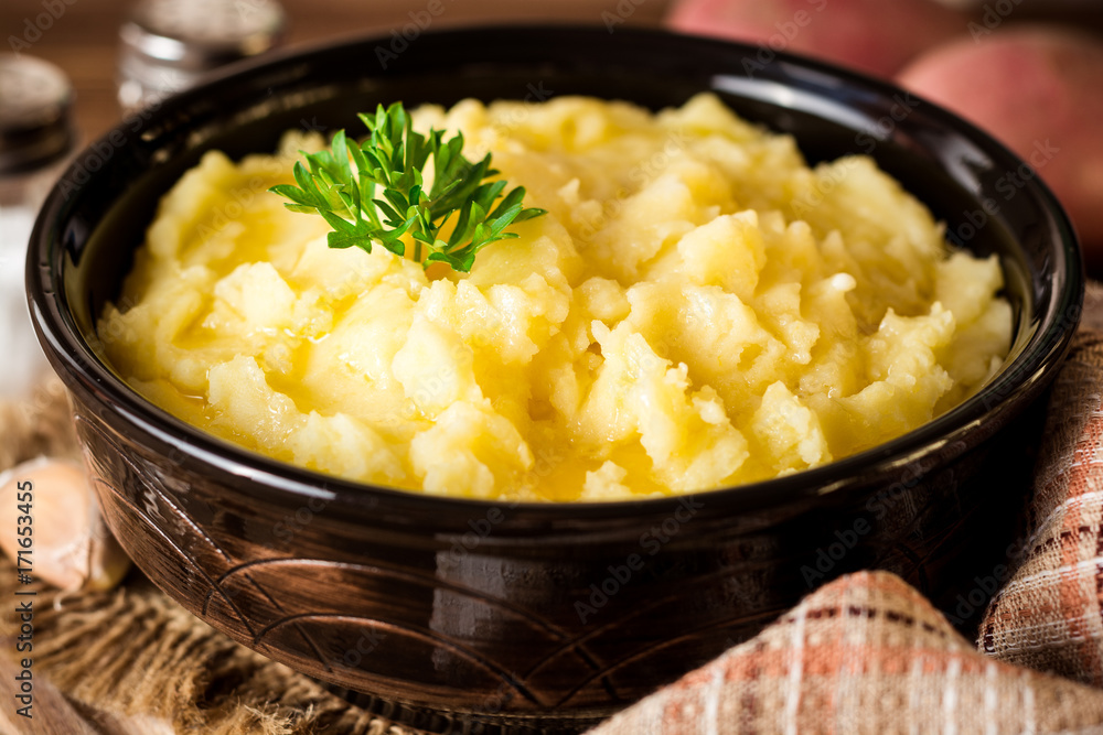 Mashed potatoes with butter and fresh parsley in bowl on rustic wooden table Mashed potatoes with butter and fresh parsley in bowl on rustic wooden table