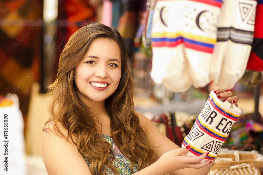 Close up of a beautiful woman holding an andean traditional handbag clothing textile yarn and woven by hand in wool, colorful fabrics background