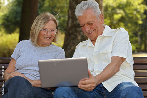 Elderly couple with a laptop outdoors. Happy, Healthy and Active Senior Living concept