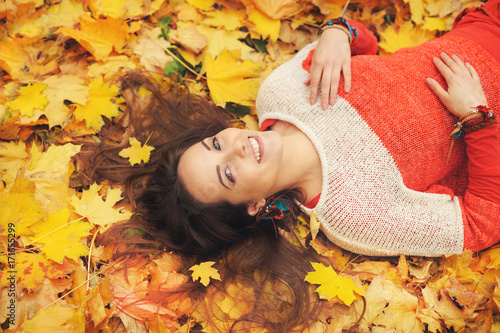 Smiling happy womanl portrait, lying in autumn leaves photo