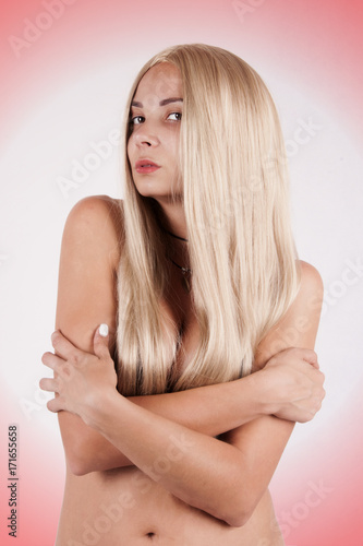 naked girl in a black livery with long blond hair crossed her arms over her chest against a white background