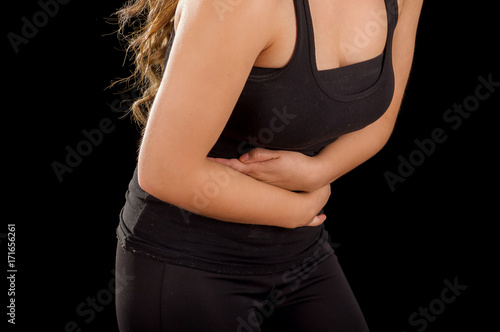 Beautiful young woman with stomach ache or nausea in a black background photo