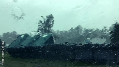 Portable toilets installed at a Florida highway rest area are topped in the wind, viewed through a curtain of rain pouring down the windshield during Hurricane Irma