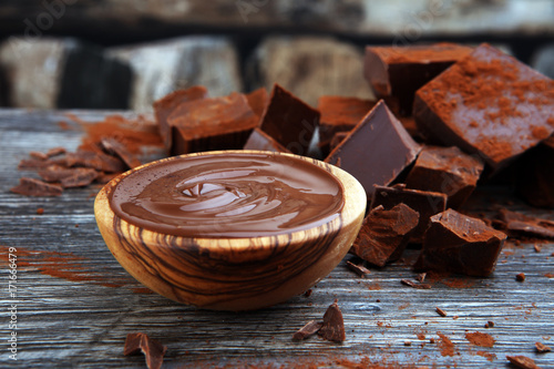 Chocolate cream melted, chocolate pieces and chocolate powder on wooden table