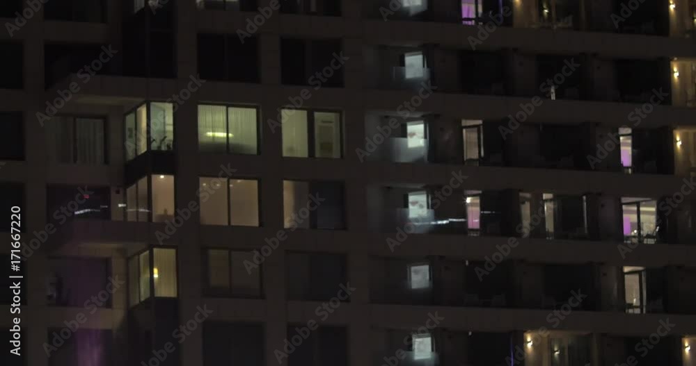 Panning shot of multistorey hotel building. Windows illuminated at night Panning shot of multistorey hotel building. Windows illuminated at night
