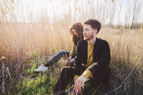 Young couple sitting among tall dry grass