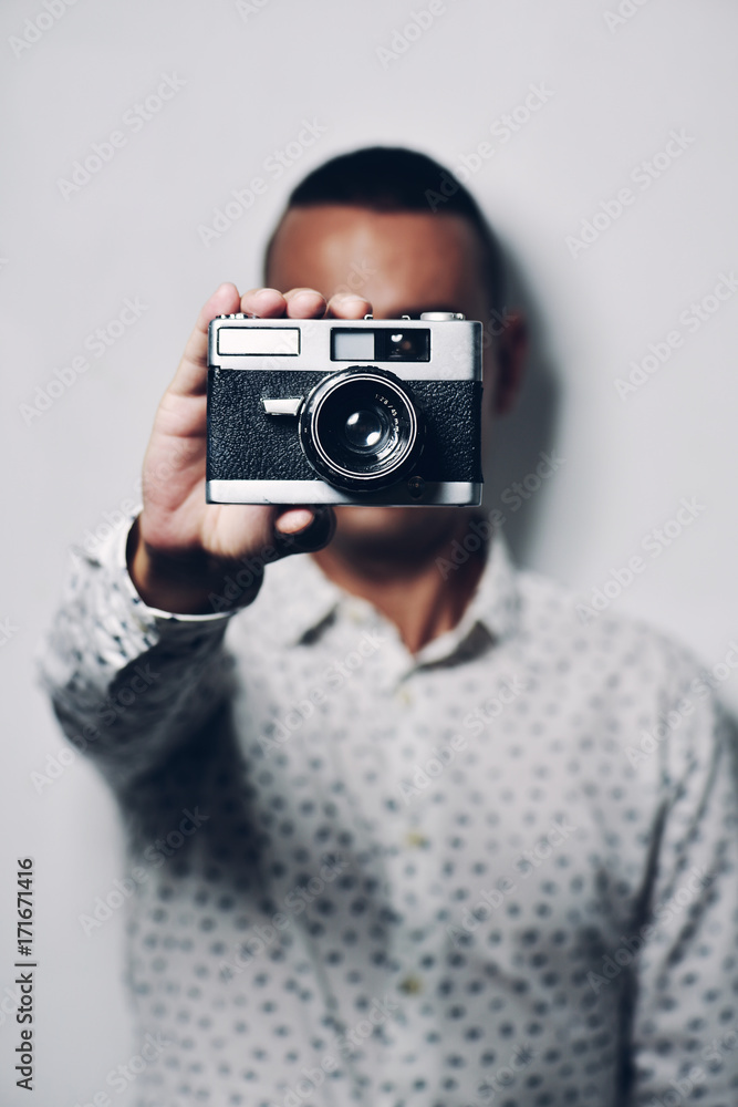 Man holding old camera while standing against white background Man holding old camera while standing against white background