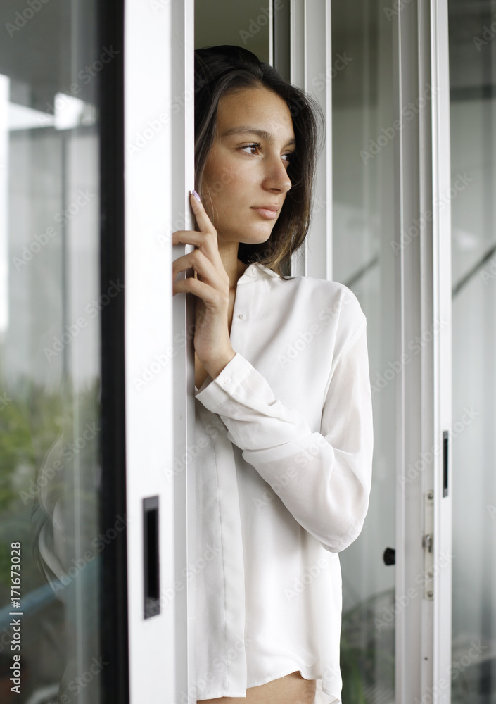 young woman in white shirt in between sliding doors young woman in white shirt in between sliding doors