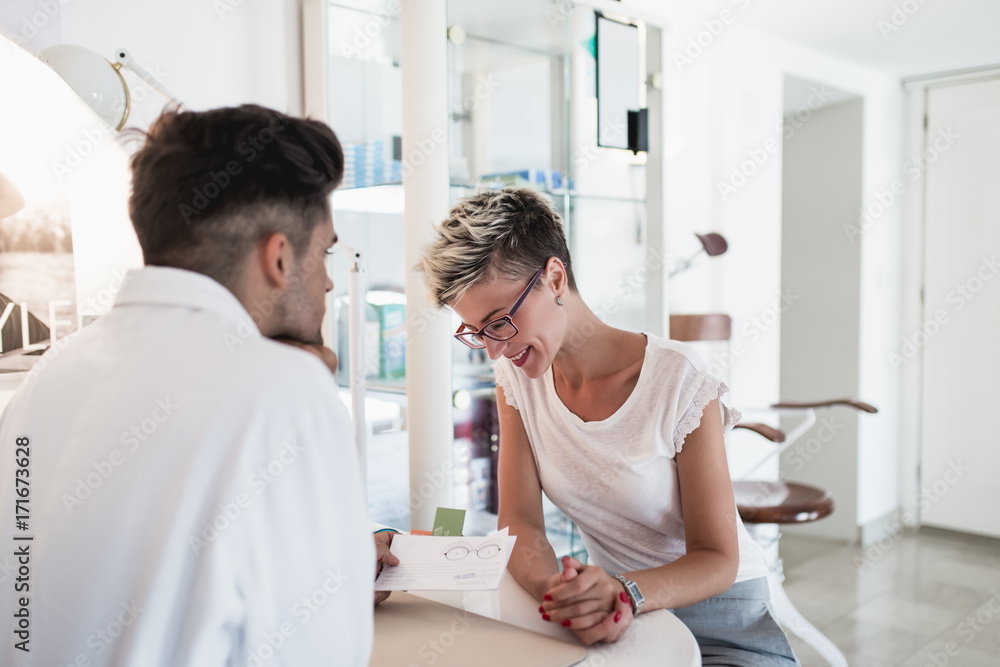 Obraz premium Male optometrist talking with his patient at eye clinic. 