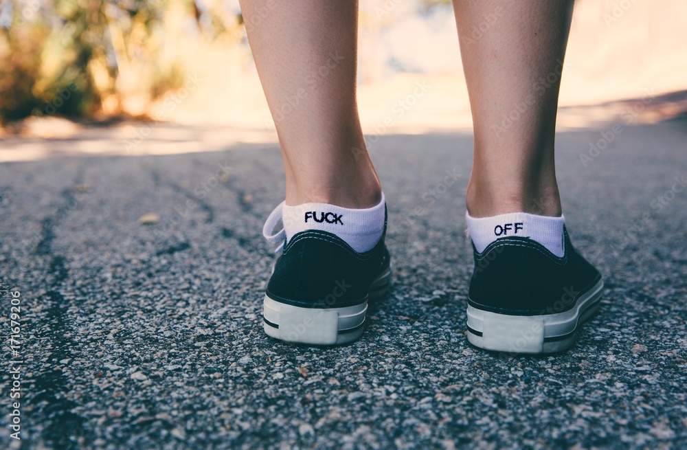 Feet facing forward with socks that say Fuck Off Feet facing forward with socks that say Fuck Off