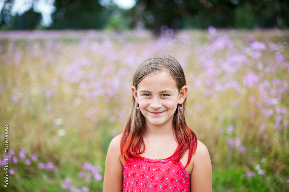 Girl with red tipped hair stands in front of flowery meadow Girl with red tipped hair stands in front of flowery meadow