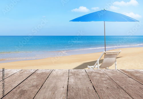 Fototapeta Naklejka Na Ścianę i Meble -              Empty perspective old wooden balcony terrace floor with white wooden beach chair and blue parasol on tropical beach with blue sky 