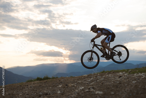 Man jumping on mountain bike with sunset in the background