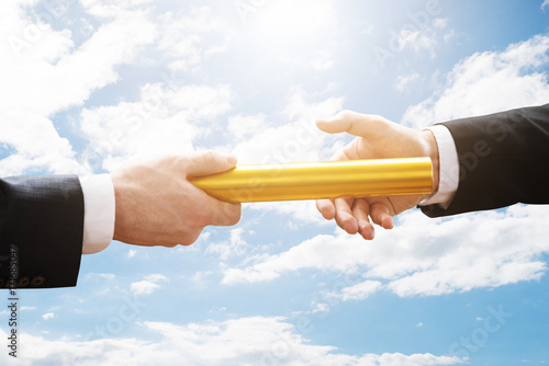 Two Hands Passing A Golden Relay Baton photo