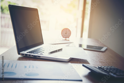 Portrait of businessman with laptop, finance graph and writes on a document at  office.