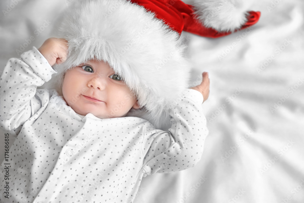 Cute little baby in Santa hat on white sheet
