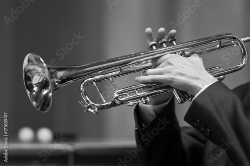 Hands of a musician playing on a trumpet closeup in black and white tones