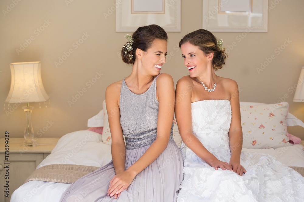 Happy bride and bridesmaid while sitting on bed at home Happy bride and bridesmaid while sitting on bed at home