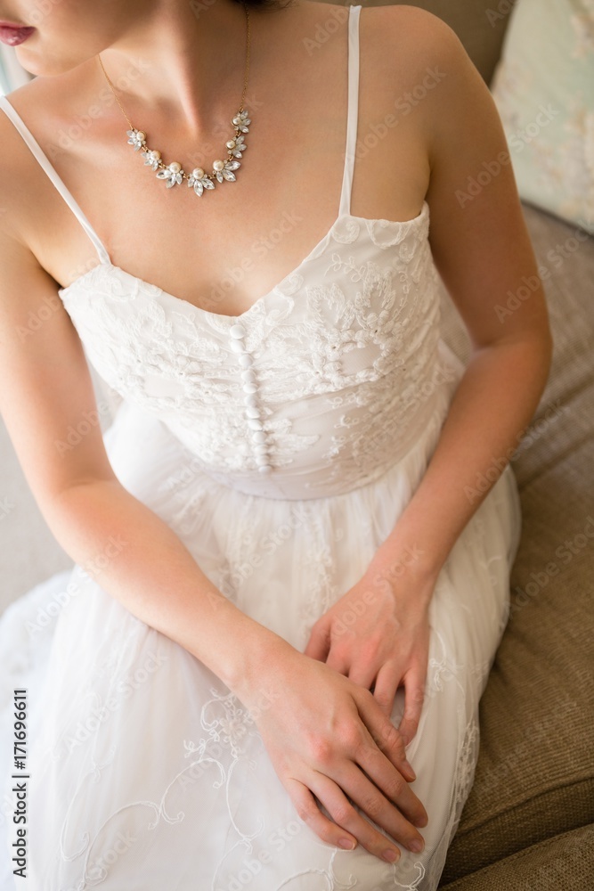 Midsection of beautiful bride wearing necklace sitting on sofa
