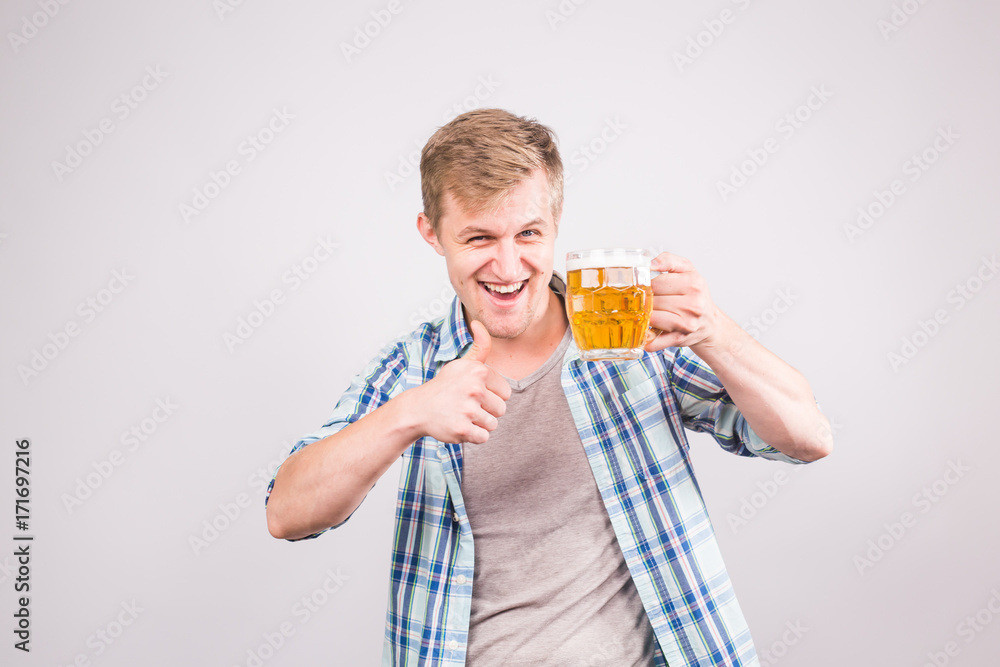 Cheerful young man holding a beer mug full of beer and smiling on white background Cheerful young man holding a beer mug full of beer and smiling on white background