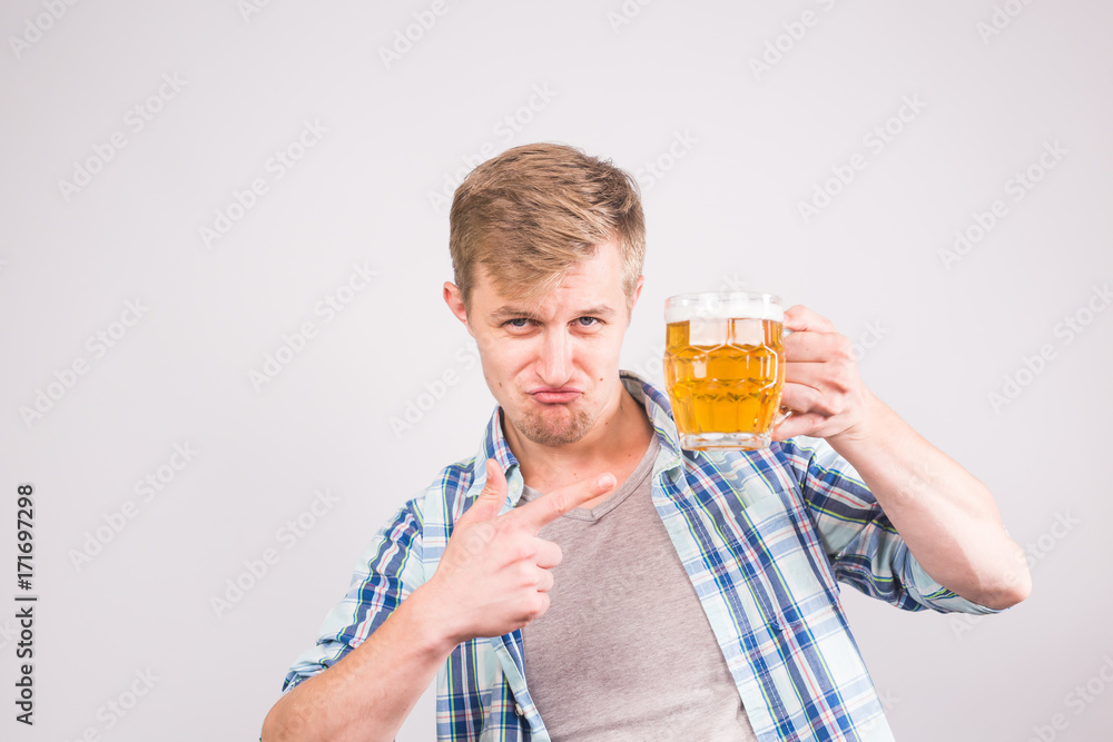 Happy young man holding and pointing on a beer mug Happy young man holding and pointing on a beer mug