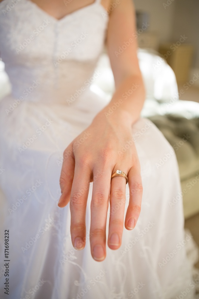 Midsection of bride showing wedding ring while sitting on bed Midsection of bride showing wedding ring while sitting on bed