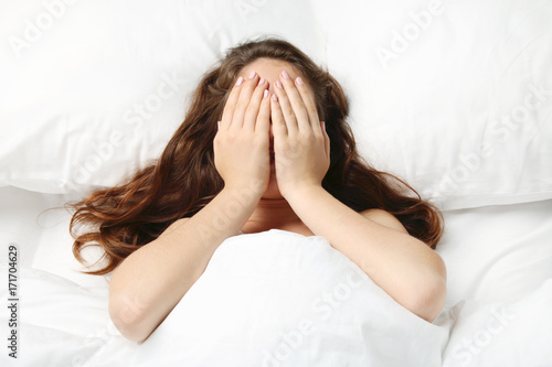 Sick young woman lying in white bed