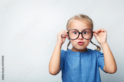 Portrait of little girl with glasses on grey background