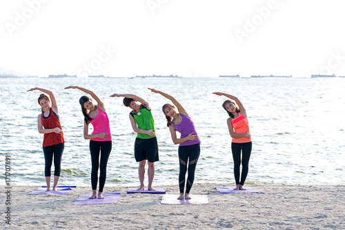 Asia people group making warrior pose on beach, fitness, sport, yoga and healthy lifestyle. Healthy Concept