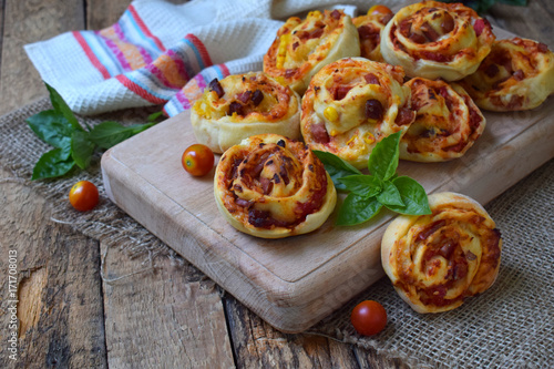 Buns of yeast dough with tomatoes, ham and cheese on a wooden background. Mini pizzas. homemade baking