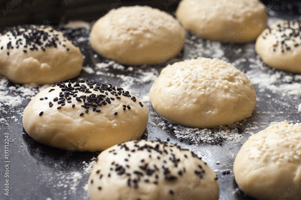 Ταπετσαρία Burger bun dough or batter ready for the oven, sprinkled with sesame seeds
