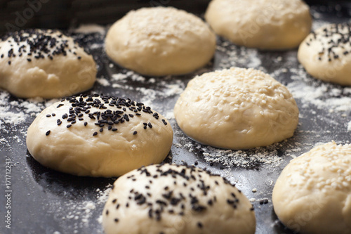Tablou pe pânză Burger bun dough or batter ready for the oven, sprinkled with sesame seeds