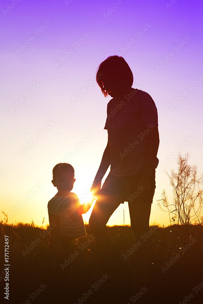 Silhouette of a happy woman with her child at sunset.