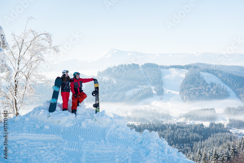 Young couple snowboarders enjoying beautiful natural landscape, resting on top of the mountain on a sunny winter day copyspace travelling snowboarding lifestyle recreation vacation holidays