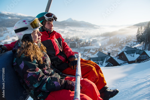 Close-up of couple man and woman snowboarders on a cable ski lift in the morning in Bukovel enjoying a beautiful view of the Carpathian Mountains copyspace recreation active sport seasonal concept