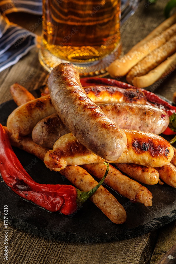 Grilled sausages with a glass of beer on a wooden table. Rustic style.