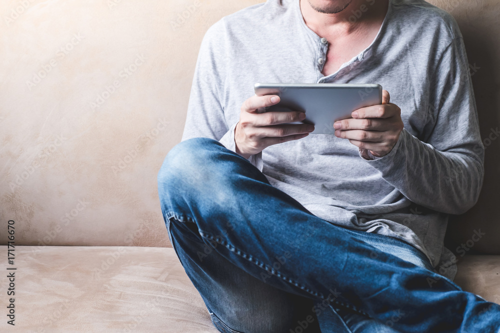 Casual young man using tablet on sofa at home. Casual young man using tablet on sofa at home.