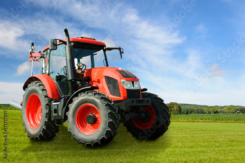 Composite image of a modern red agricultural generic tractor on a green field on a sunny day. 