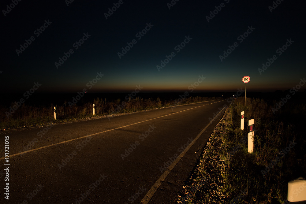 Rural Asphalt Road With Road Sign Under Dark Blue Sky At Night.