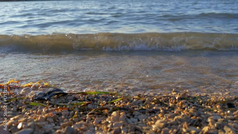 small waves splashing sandy beach at beautiful sunset. sun making lens flares. slow-motion hd